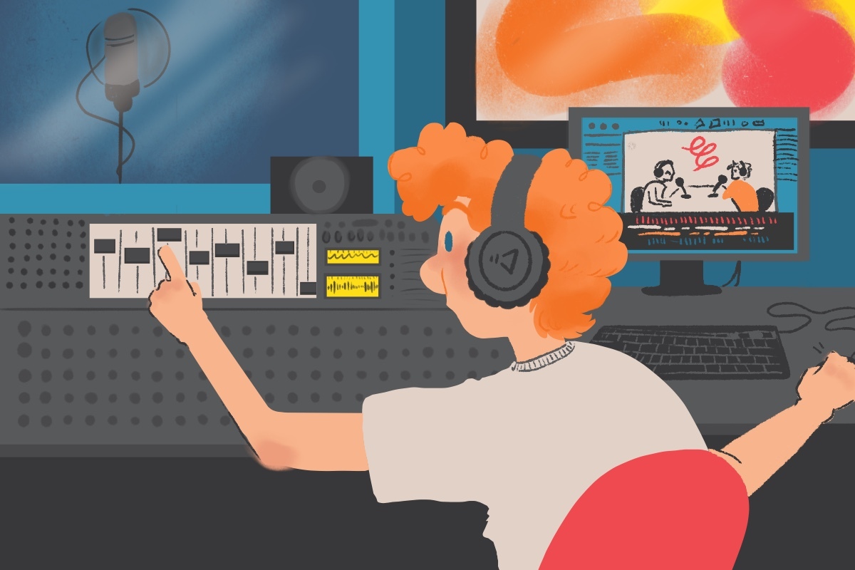 A red-haired man with headphones sits in the producer's room of a sound recording booth, his right hand on a computer mouse and his left on the sliders of a large soundboard. The computer (right) shows video capturing of two people talking on a podcast set. On his left is the large soundboard and a window showing inside a sound recording space with an empty microphone.